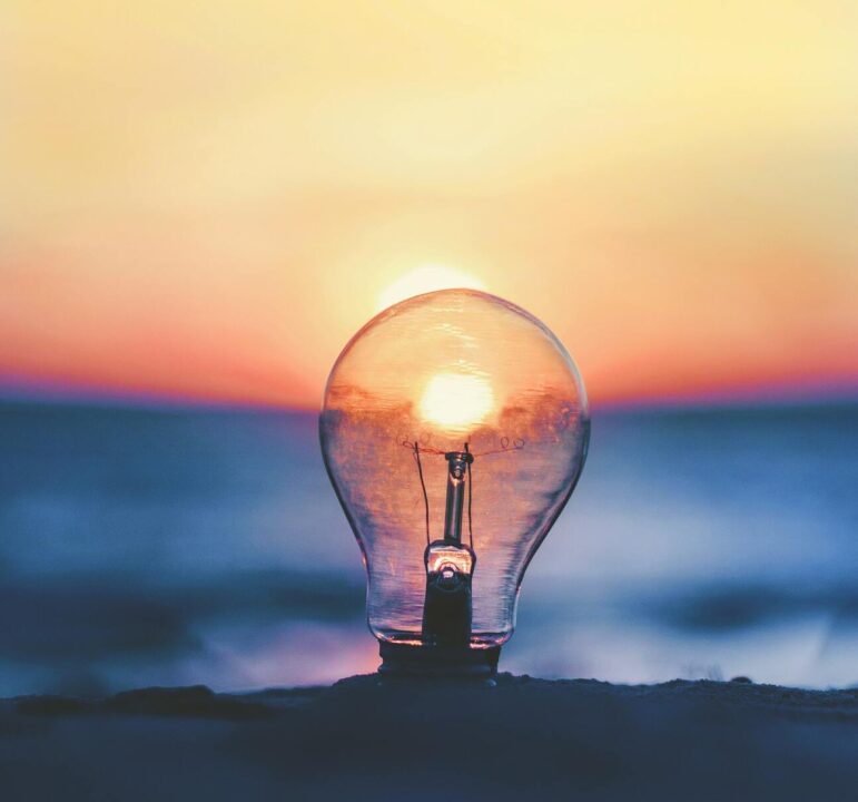 Light bulb with sun flare and sunrise in background